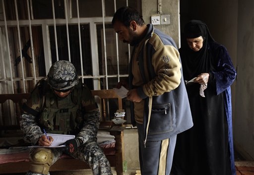 Caption: An Iraqi police officer takes census information from a family in Mosul in March 2009., Credit: Photo courtesy of Associated Press