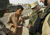 Caption: An Iraqi interpreter helps a US soldier to inspect a man's identity papers., Credit: AP Photo/Jacob Silberberg