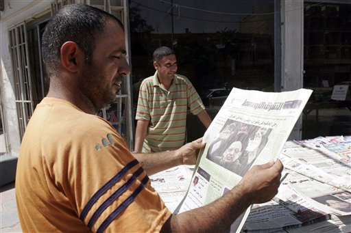 Caption: An Iraqi man reads a newspaper in Baghdad., Credit: Associated Press