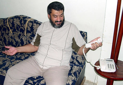 Caption: An Iraqi holds up his non-functioning phone., Credit: Associated Press