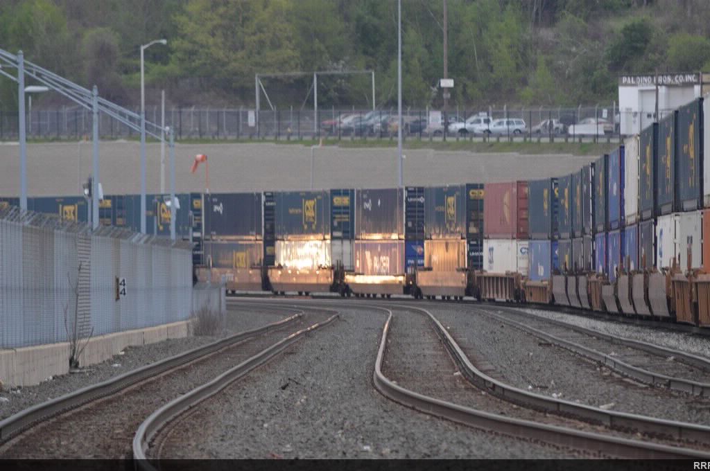 The headlights of an approching train light up some containers. 