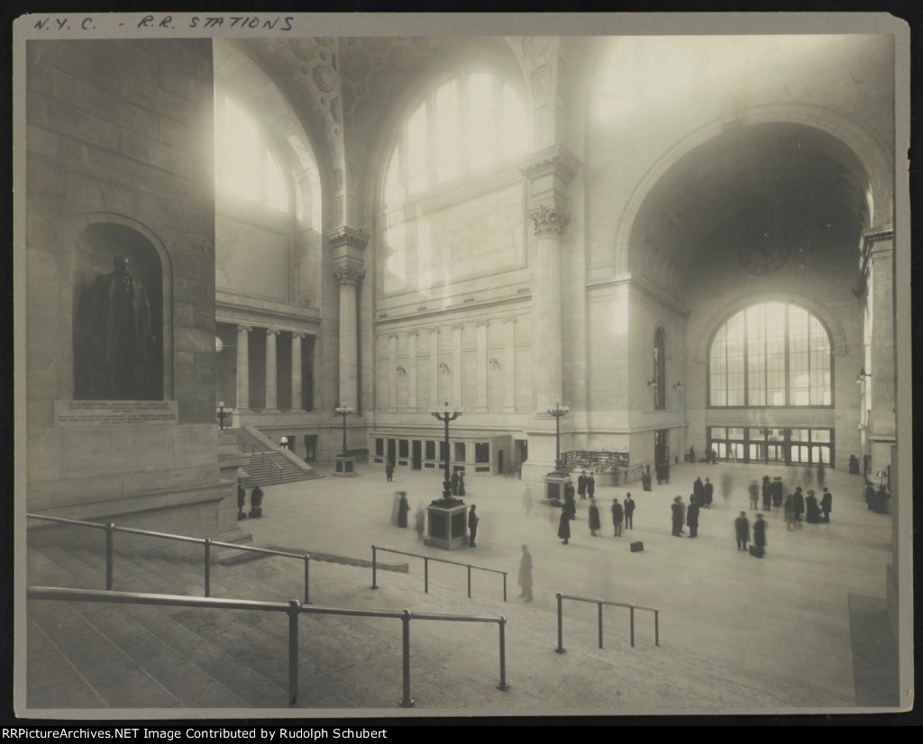 Passengers in the waiting room at Pennsylvania Station, New York, New York, with statue of Alexander Johnston Cassatt, president of the Pennsylvania Railroad Company, in niche on the wall