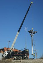 Headless signal mast is moved into position to be lowered.