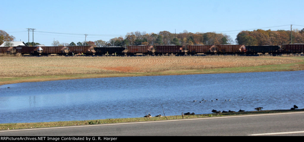 Looking across a pond in Gretna at ballast train 92Q dumping ballast on new double track