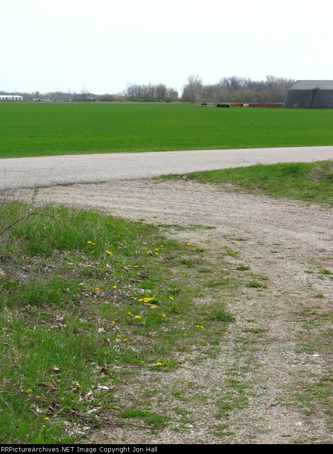 Southward across Dodge Rd and the fields towards the odvious path through the trees