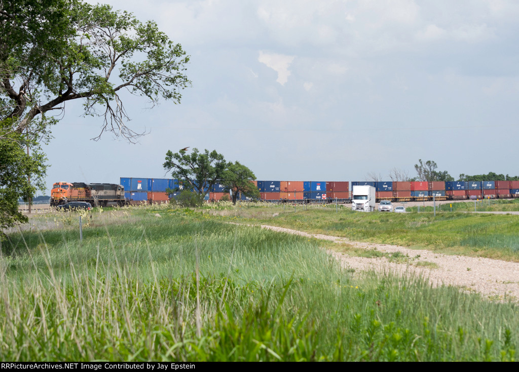 An eastbound intermodal hugs US 287 as it rounds a big curve