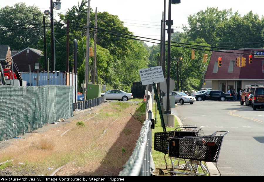 a string of ballast cars waits for the lights to turn red before shoving west.