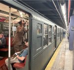 Side view of an Arnine Car with a lot of people inside-the train is stopped at 2nd Ave Station