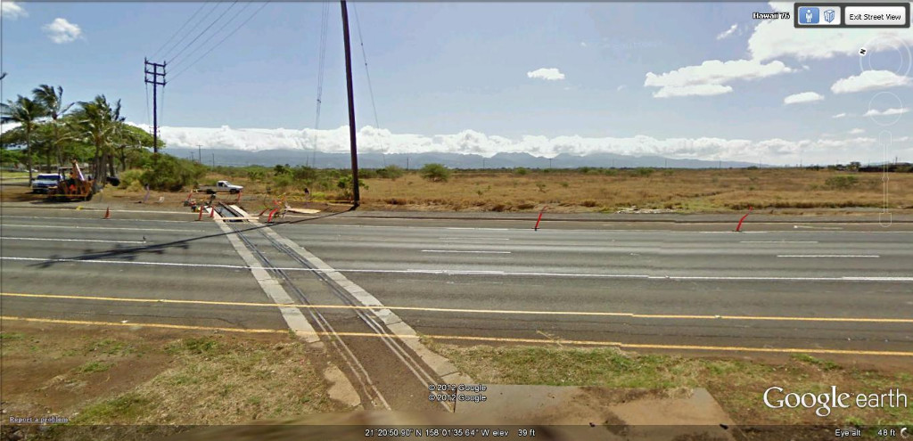 Hi 76 Grade Crossing facing East, Track covered by brush.