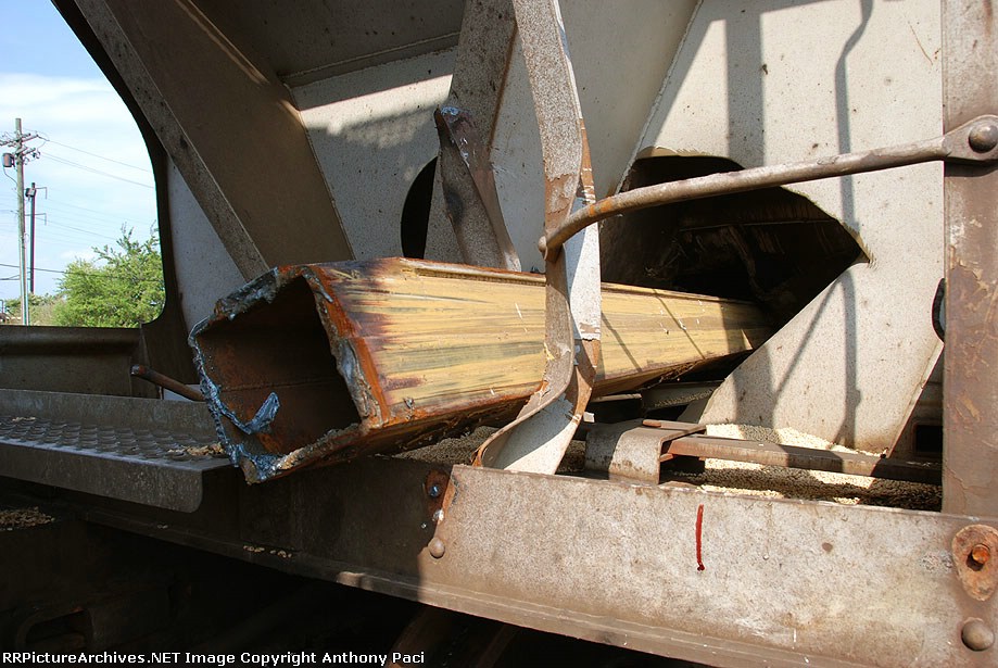 A piece of a stack car that punctured this covered hopper