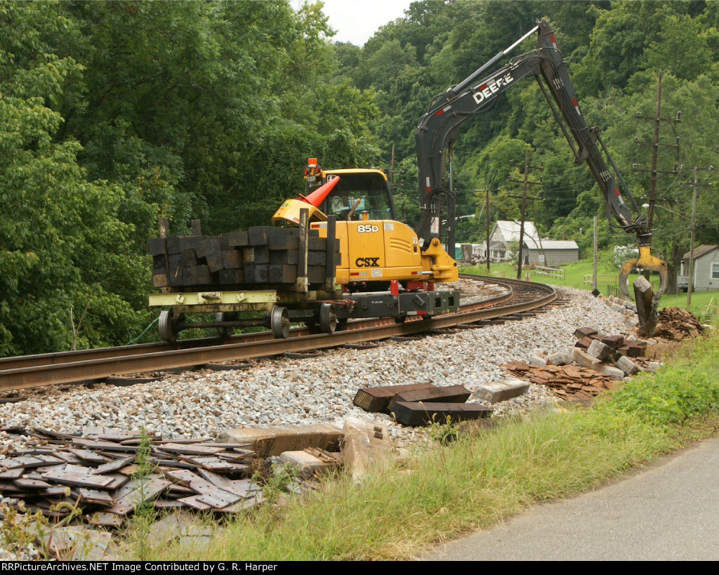 Street level view of tie grabber setting discarded concrete tie off to the side