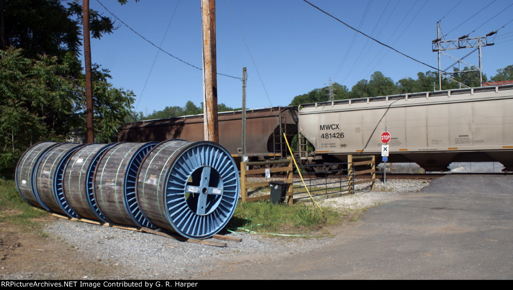 Reels of cable for APCO transmission line upgrade await being strung as grain train whizzes by