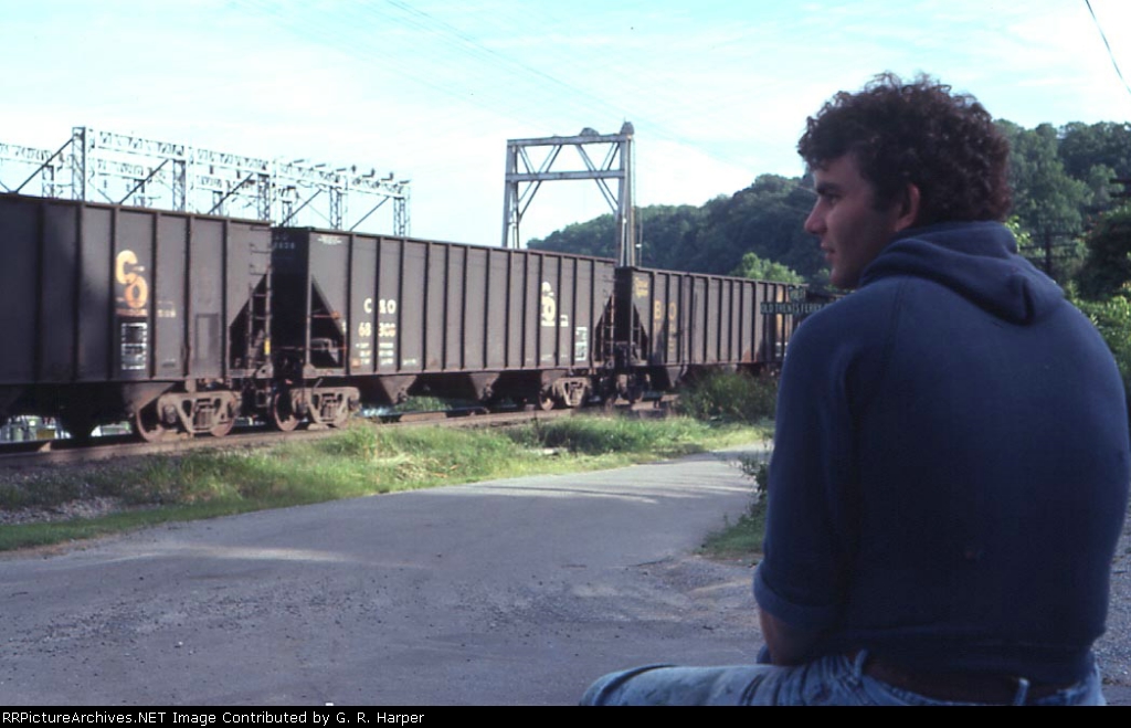 My.younger brother Tom, pictured elsewhere in this album, watches some empty C&O / Chessie hoppers go west.