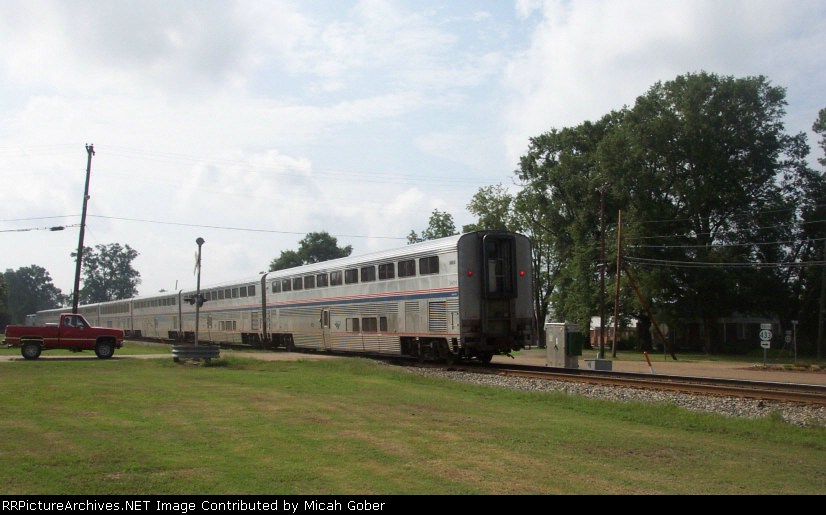 A red pickup truck waits as Amtrak The City of New Orleans passes by 