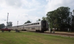 A red pickup truck waits as Amtrak The City of New Orleans passes by 