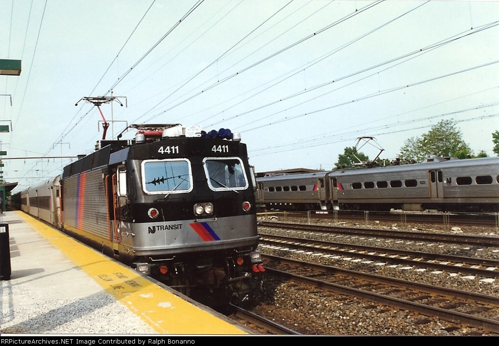 4411 arrives   at the station as a NY bound set of arrows departs in the rear