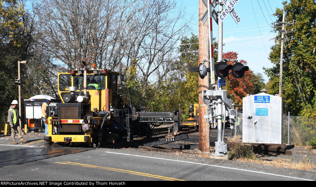 TX 801 is seen inserting new ties at the Station Road grade crossing