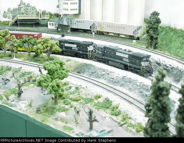 C39-8 and GP38 run a way freight as Alabama Co-Op towers in the background