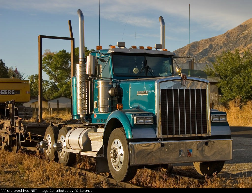 Kenworth Hi-Railer with a John Deere Track-hoe in tow on a flat car.