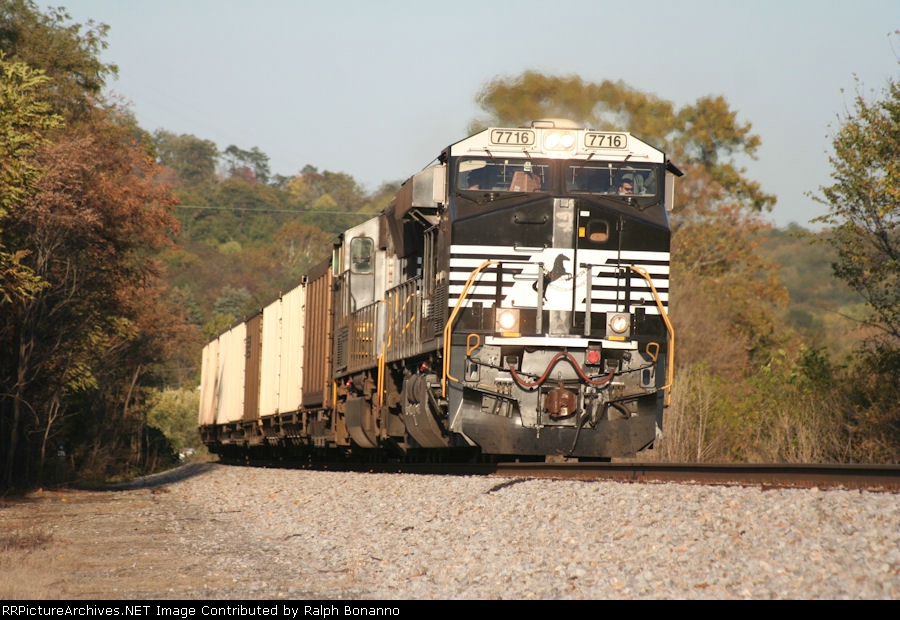 An empty hopper train heads upgrade and into the afternoon sun, having recently departed Roanoke