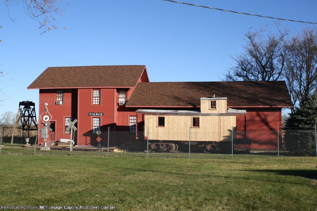 The Two-Story C&NW Depot, Now Located in a City Park, with a Former NP Caboose Undergoing Restoration