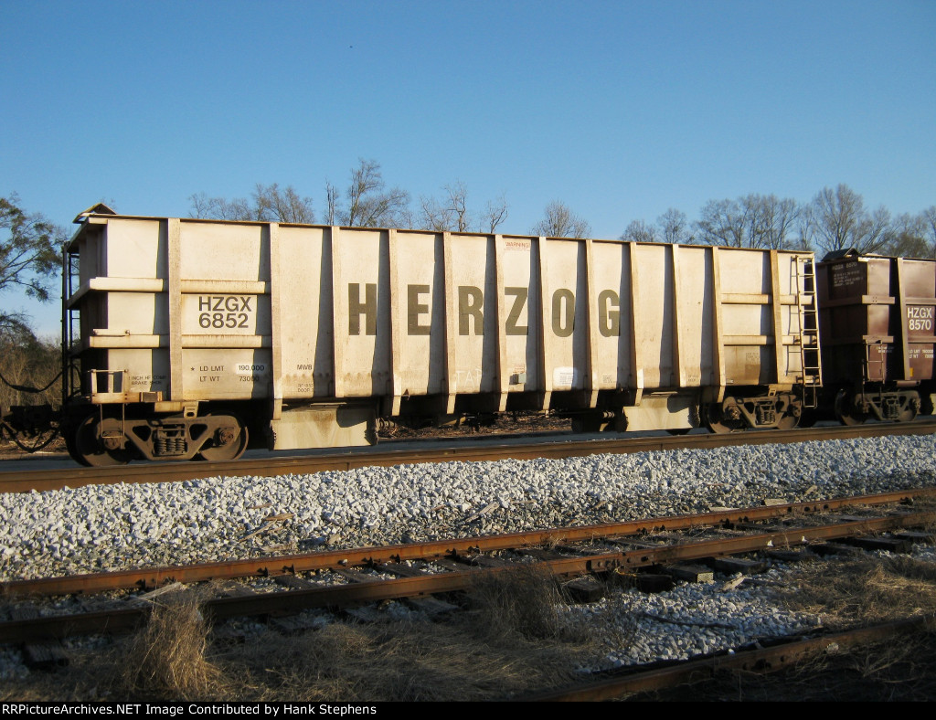 Portrait shot of Herzog Ballast train black and white car in siding at West Point, GA