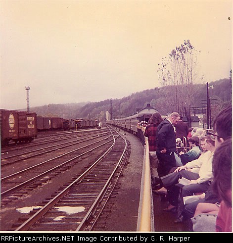 Open-air cars are coupled and occupied at the station