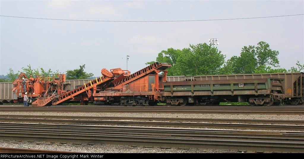 Ballast cleaner has lowered side piece to right above ballast, ready to move,