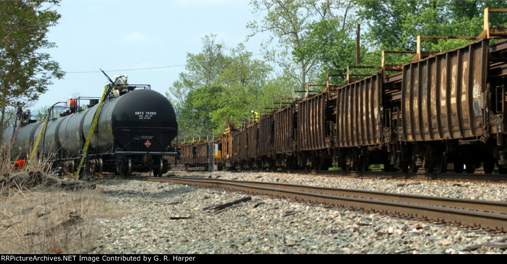 Middle of rail train, B01406, passing healthy tank cars being loaded with derailment oil