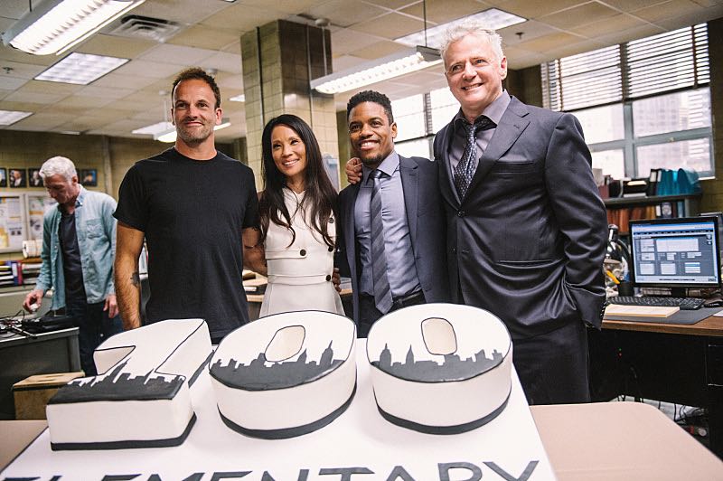 "Henny Penny The Sky Is Falling" -- The cast of ELEMENTARY celebrates their milestone 100th episode with a cake-cutting ceremony Pictured (L-R) Picture (L-R) Jonny Lee Miller, Lucy Liu, Jon Michael Hill and Aidan Quinn Photo: Michele Crowe /CBS é2016 CBS Broadcasting Inc. All Rights Reserved.