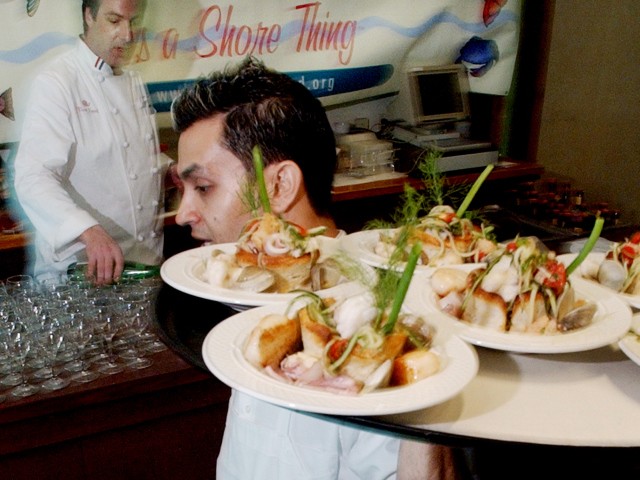 Waiter carries tray of fish to customers