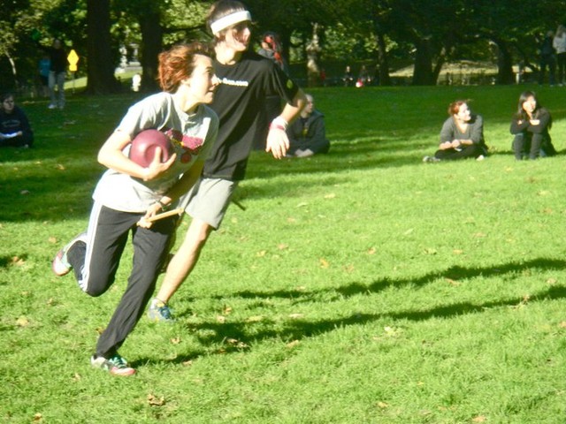 An NYU Quidditch player clutches a quaffle ball as she dashes down the field during game practice.