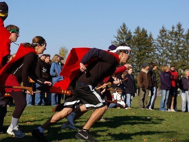 Straddling broomsticks and donning red capes, Quidditch teammates gets off to a running start during a game.