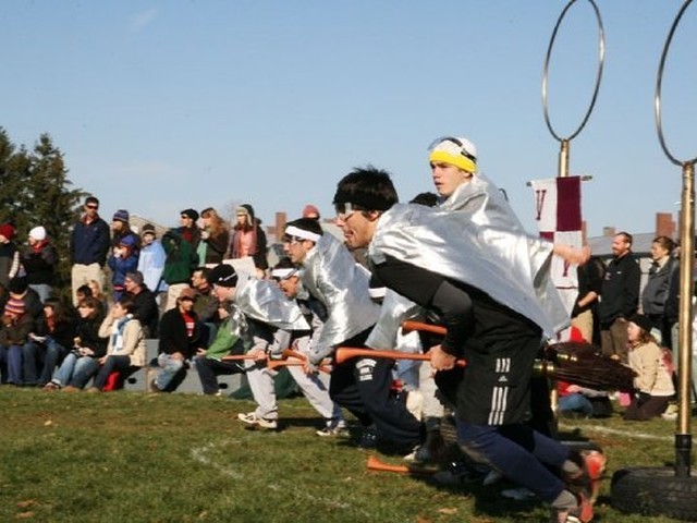 Crowds gather around the team as its members take off running, dressed in silver capes.
