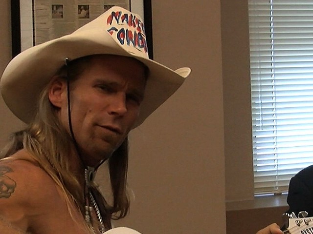 The Naked Cowboy sits with his attorney at a press conference announcing his lawsuit against Sandy Kane.