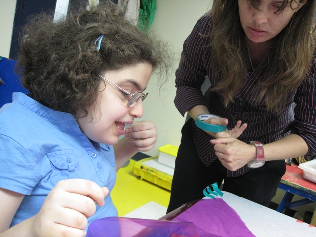 Art therapist Sarah Valeri, right, guides student Subhia Ahmad, 13, through an art project with cellophane.