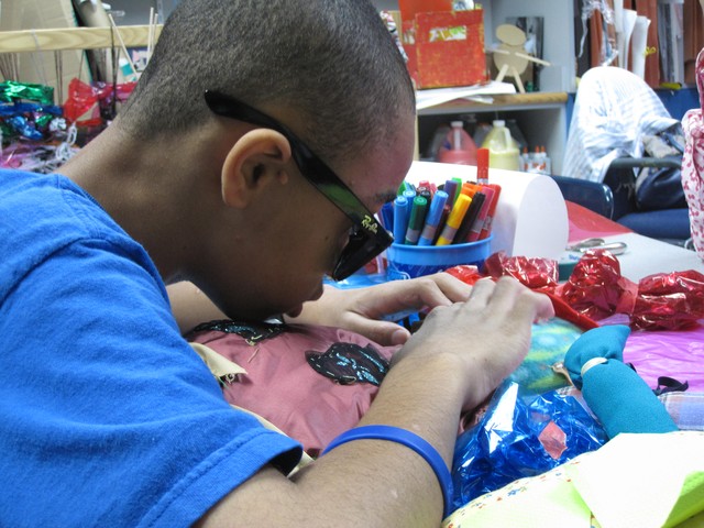 Visually impaired student Eli Jackson uses both his hands and eyes to look at a doll he made in art class.