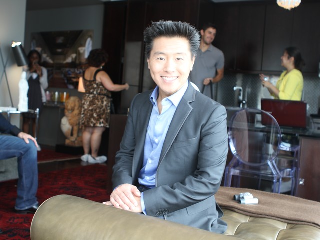 HGTV interior designer Vern Yip poses in the living room/dining room on a multifunctional couch.