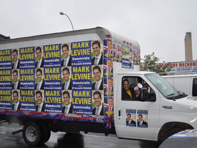 A cube truck papered with Levine posters leads the caravan down Broadway from 215th Street.