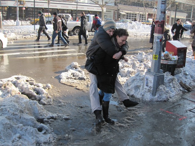 A woman gives a man a lift through a massive slush puddle at the corner of Houston and Allen streets.
