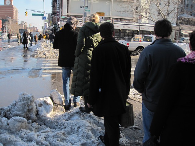 Pedestrians created a traffic jam trying to find a way around the puddle.