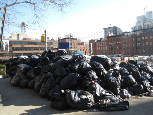 More than 100 bags of garbage sat outside the Southbridge Towers at Pearl and Beekman streets Monday morning.