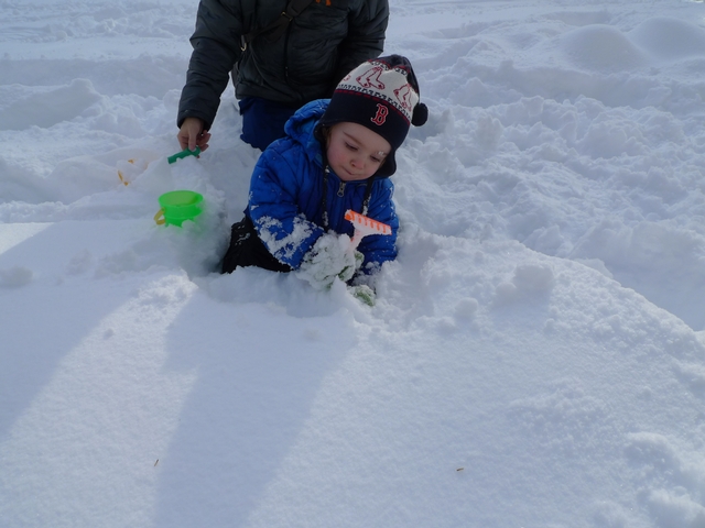 Yale Block, 19 months old, practices scooping skills with sand toys in the snow in Central Park.