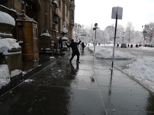 A doorman at The Dakota warms up his pitching arm with a snowball.