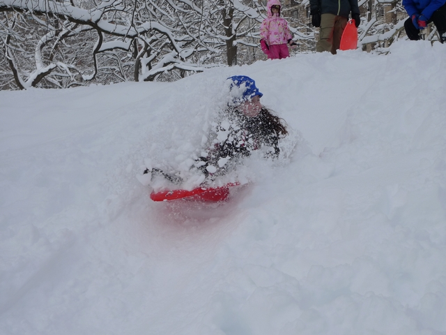 Anna Rogoff, a 7-year-old with a day off school, sails through a snow shower on a Central Park sledding hill.