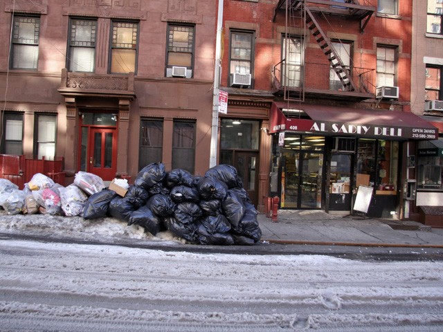 Garbage sat in front of residences and business on West 56 Street Monday morning. The next pickup for the street was scheduled for Tuesday, according to the Department of Sanitation's website.