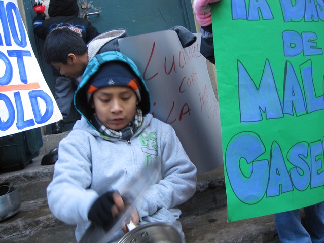 A young resident of 21 E. 115th St. bangs a pot in a protest outside of his building.