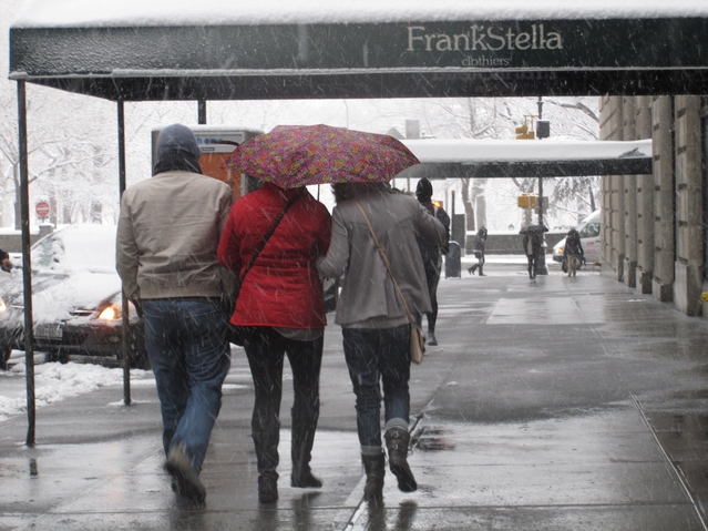 Pedestrians huddled under an umbrella near Central Park during Monday's snowstorm.
