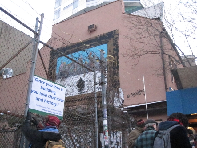 A demonstrator attached a sign to the fence surrounding 35 Cooper Square.