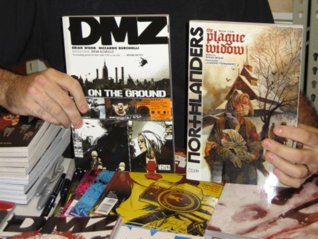 Comic writer Brian Wood holds up some of his most famous titles, 